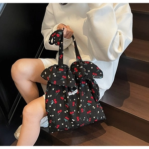 Detail of floral tote bag with cherry prints and bow handle on wooden stairs