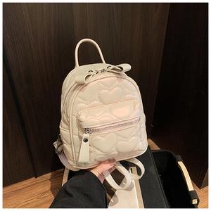 Detail of cream white mini backpack featuring heart quilting and a bow top handle