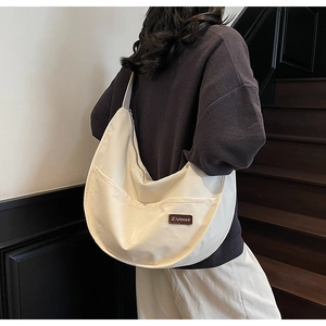 Detail of a large off-white nylon crescent tote bag showing the textured fabric and logo