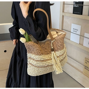 Detail of woven straw tote bag with color blocking design and long fringe tassel