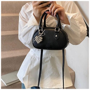 Détail du mini sac noir en cuir grainé avec pendentif coeur argenté sur le modèle