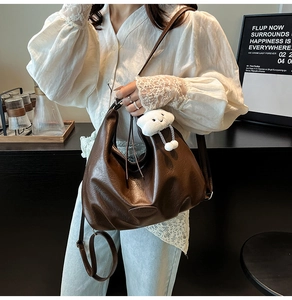 Détail du cabas en simili cuir marron foncé avec charm en peluche dans un cadre de café
