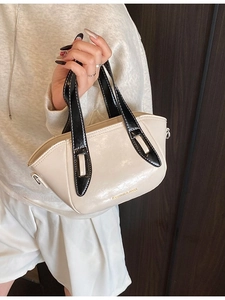 Chic cream white and black contrast bucket bag with gold lettering shown from a front angle