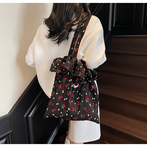 Close-up of black floral tote bag with red cherry print and ruffled edge on staircase