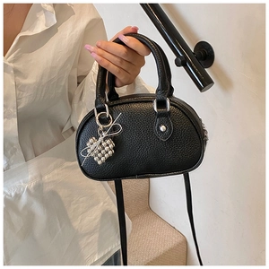 Détail du mini sac polochon noir motif litchi avec breloque cœur argentée élégante