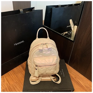 Detail of cream white mini backpack with heart-shaped quilted pattern and silver zipper