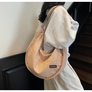 Detail of adjustable strap and front pocket on beige nylon crescent hobo tote bag