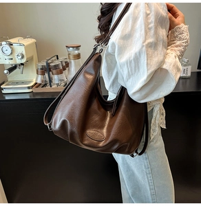 Vue détaillée du sac hobo en cuir souple marron foncé sur un comptoir de café