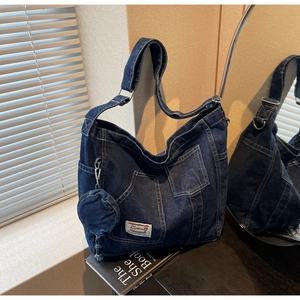 Dettaglio borsa hobo in denim blu con tasca esterna, logo e portamonete coordinato