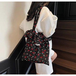 Close-up of black floral tote bag featuring cherry print and stylish ruffled edges