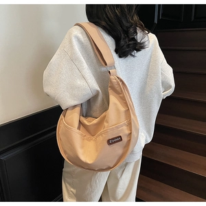 Model wearing a large cream nylon crescent crossbody bag with minimalist street style vibe