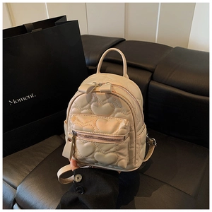 Detail of cream mini backpack featuring heart quilting and cute bow zipper pull