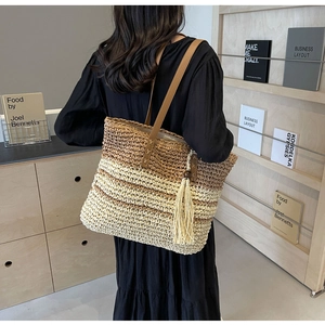 Detailed view of woven tote bag featuring gradient design and leather straps with tassels