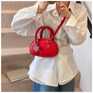 Détail du sac polochon rouge avec texture de litchi et chaîne de cœur en métal