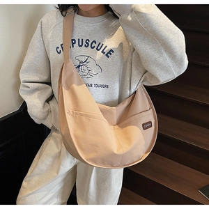 Detailed view of the beige canvas crescent tote bag featuring a leather brand tag