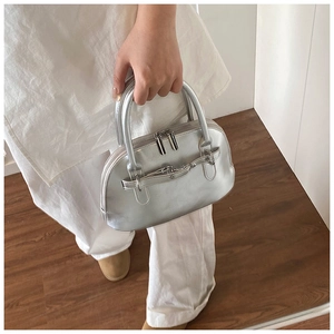 Detail of silver metallic shell bag showing dual zippers and smooth reflective finish