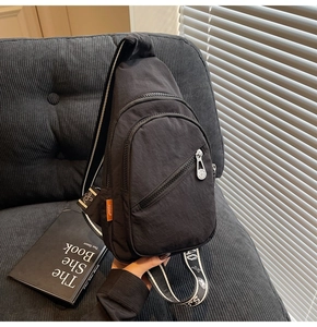 Detailed view of lightweight nylon crossbody bag featuring multi-zipper layers and woven strap