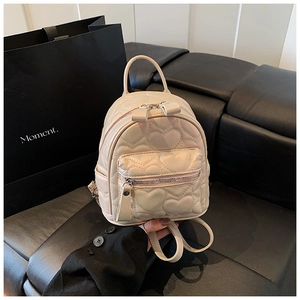 Detailed shot of beige quilted backpack with heart patterns and silver zippers