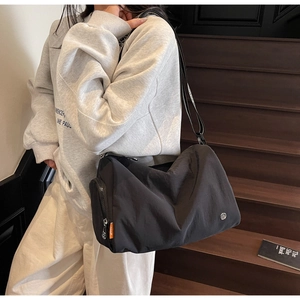 Detail of black nylon crossbody bag featuring a side zipper pocket and printed strap
