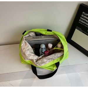 Interior detail of large neon tote bag showing storage for laptop and essentials