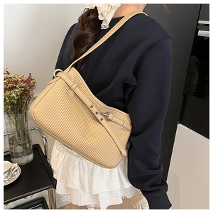 Detail of beige pleated faux leather handbag with adjustable strap and metal buckle