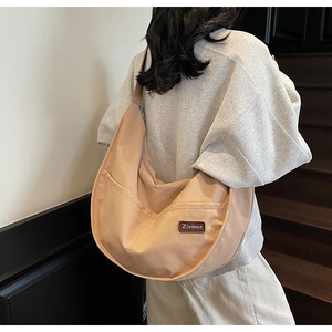 Close-up of beige nylon crescent hobo bag showing soft texture and wide shoulder strap