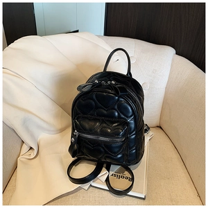 Macro view of black mini backpack featuring quilted heart pattern and silver metal zipper