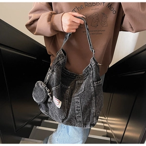 Dettaglio macro della borsa in denim nero lavato con cuciture e mini pochette