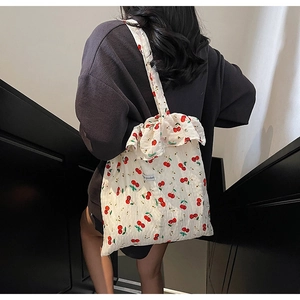 Detailed close-up of white cherry print canvas tote bag with ruffled edges and texture