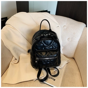 Detail of black mini backpack featuring heart quilted pattern and ribbon bow decor
