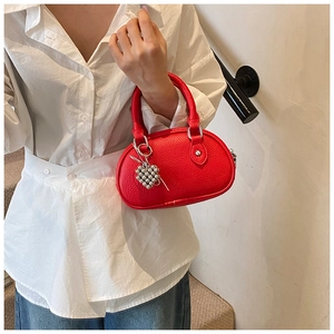 Détail du sac polochon rouge en cuir grainé avec pendentif coeur et garniture argentée
