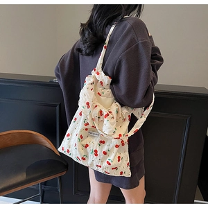Detail of white canvas shoulder bag featuring cherry prints and textured fabric finish