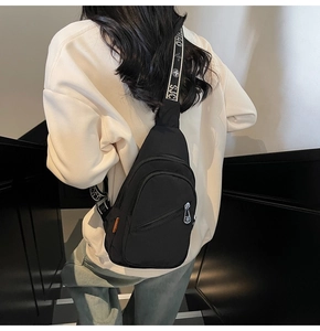 Detail of lightweight black nylon chest bag with lettered strap and multi-zipper pockets