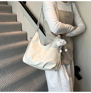 Détail du sac hobo en cuir crème avec pendentif nuage en peluche et logo embossé