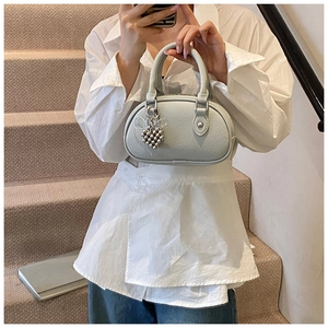 Détail du sac bleu en cuir grainé avec pendentif coeur argenté et poignée arrondie