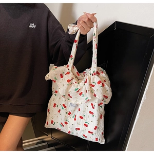 Detail of white tote bag with cherry print, magic pocket label and ruffle edges