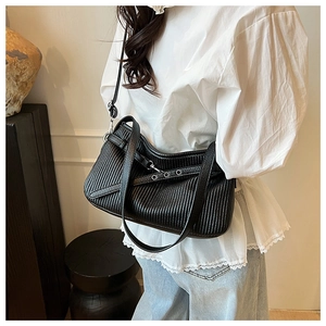 Detail of black pleated PU leather bucket bag with metal eyelets and adjustable strap