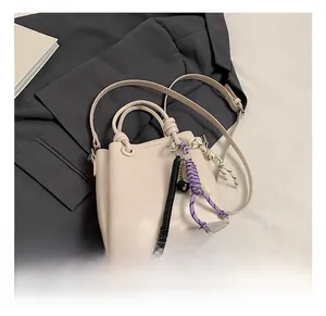 Detail of a minimalist cream bucket bag with unique purple and black woven charms