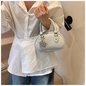 Détail d'un sac à main minimaliste en cuir grainé crème avec accessoire de charme en cœur
