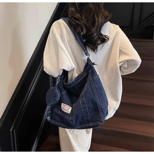 Borsa tote in denim blu scuro con portamonete coordinato indossata da una modella