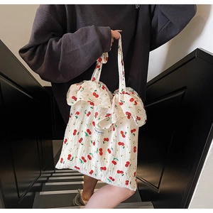 Detail view of white canvas bag with red cherry prints and ruffled wavy bag opening
