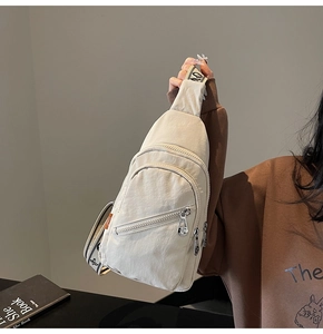 Detail of cream nylon chest bag featuring wrinkled texture and wide lettered strap