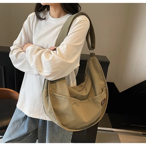 Detail view of khaki nylon crescent bag with wide shoulder strap and front pockets