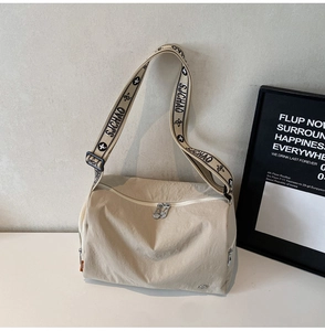 Detail of beige sporty crossbody bag featuring wide SJCHAO jacquard strap and dual zippers