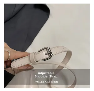 Detail of adjustable beige leather shoulder strap with polished silver metal buckle