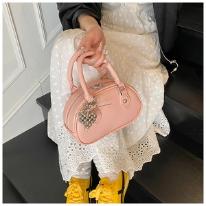 Sac polochon rose à texture litchi avec breloque cœur argentée dans un décor lifestyle