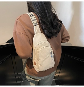 Detail of cream nylon crossbody bag with multi-zipper layers and patterned wide strap