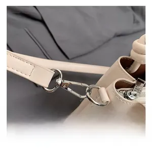 Detailed view of silver metal rotating clasp and stitching on cream bucket bag