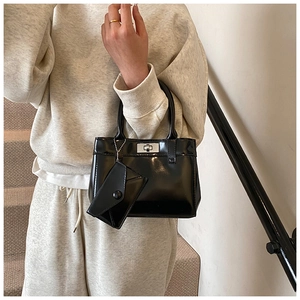 Detail of black patent leather bucket bag with silver clasp and small hanging pouch accessory