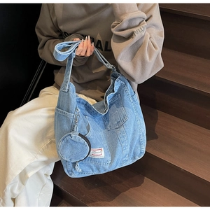 Dettaglio della borsa hobo in denim azzurro con portamonete su scale di legno